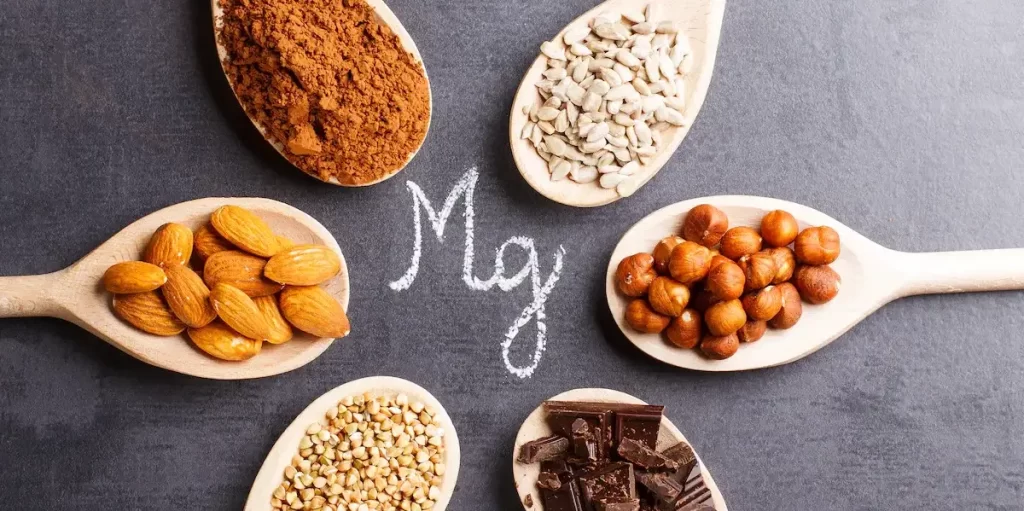 A photo of food sources rich in magnesium such as nuts, seeds, leafy green vegetables, and dark chocolate. Magnesium is an important mineral for health, responsible for energy production, enzyme regulation, and cardiovascular health. Magnesium deficiencies are common and can be caused by an imbalanced diet or chronic stress. It is important to include magnesium-rich foods in your diet or take supplements to maintain adequate levels of magnesium in the body.