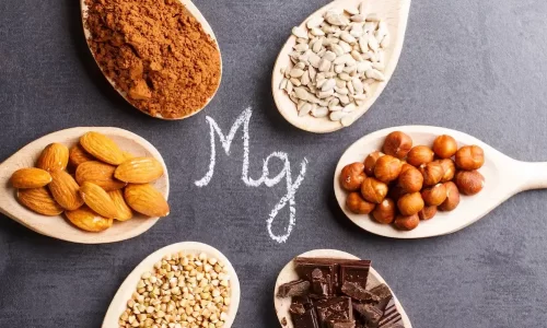 A photo of food sources rich in magnesium such as nuts, seeds, leafy green vegetables, and dark chocolate. Magnesium is an important mineral for health, responsible for energy production, enzyme regulation, and cardiovascular health. Magnesium deficiencies are common and can be caused by an imbalanced diet or chronic stress. It is important to include magnesium-rich foods in your diet or take supplements to maintain adequate levels of magnesium in the body.